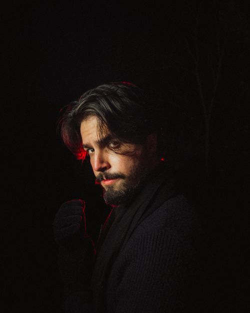 Free Dramatic portrait of a man illuminated by red light, creating a mysterious atmosphere. Stock Photo