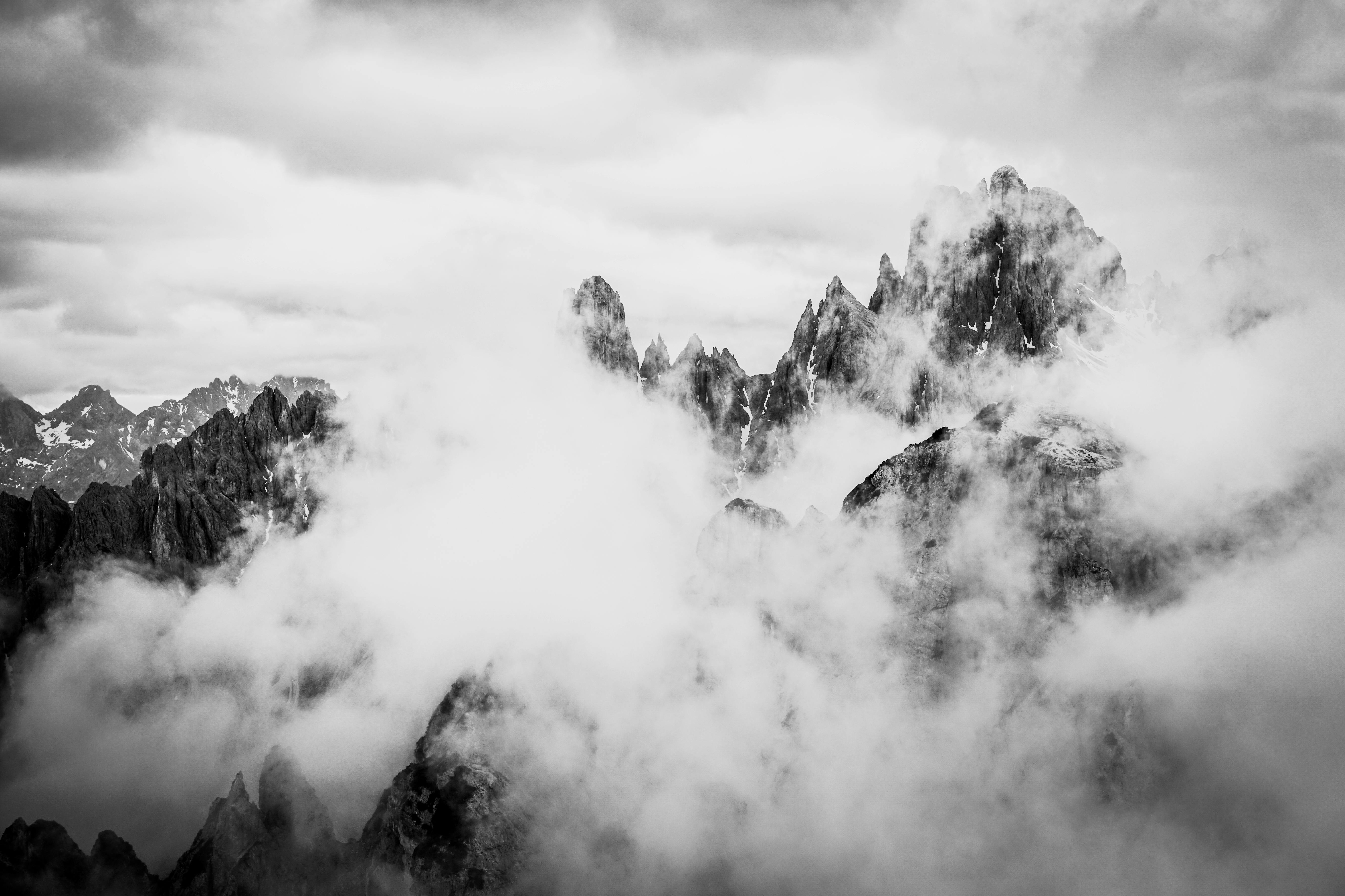 Stunning black and white photo of the Dolomites shrouded in clouds, capturing their dramatic peaks.