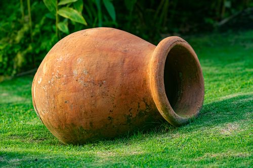 Free A rustic clay pot lies on vibrant green grass in a garden setting, evoking a peaceful outdoor ambiance. Stock Photo