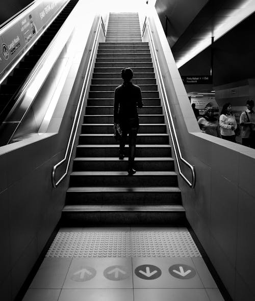 Grayscale Photography of Person Walking on Stairs
