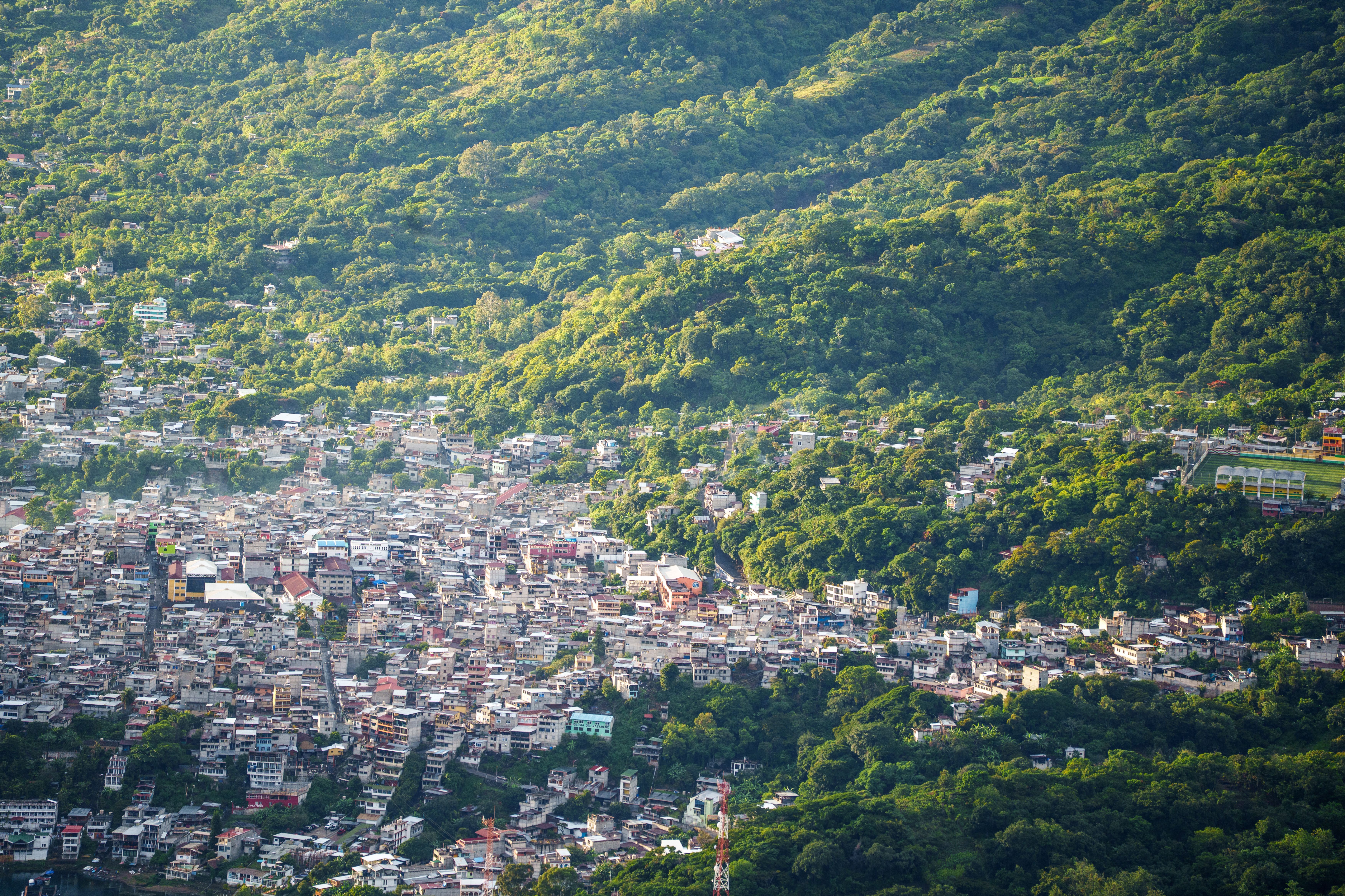 Aerial view of a city nestled in a green hillside, showcasing the blend of urban and natural environments.