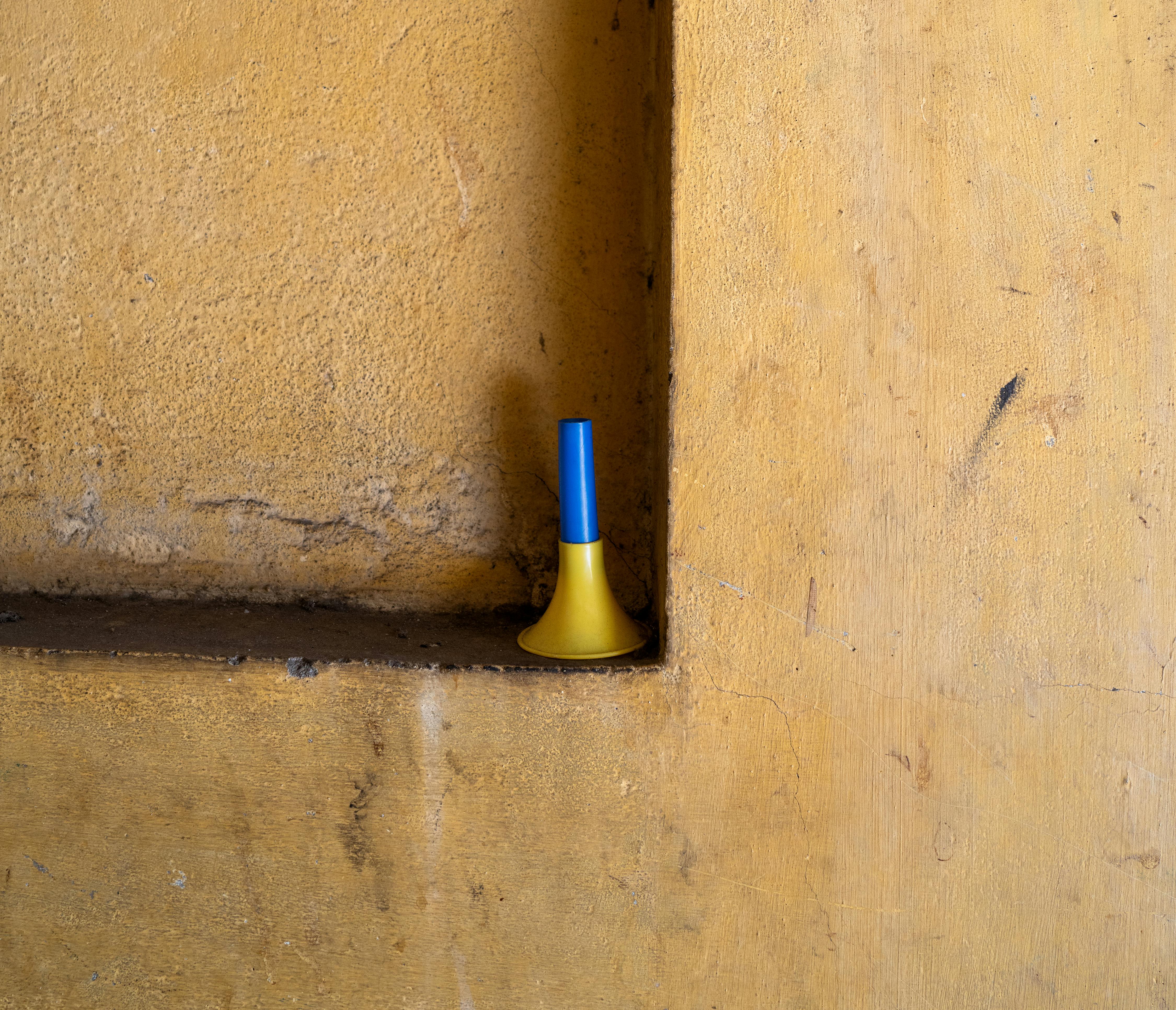 Gratuit Une scène minimaliste et vibrante d'une corne de jouet bleue contre un coin de mur jaune texturé au Vietnam. Photos