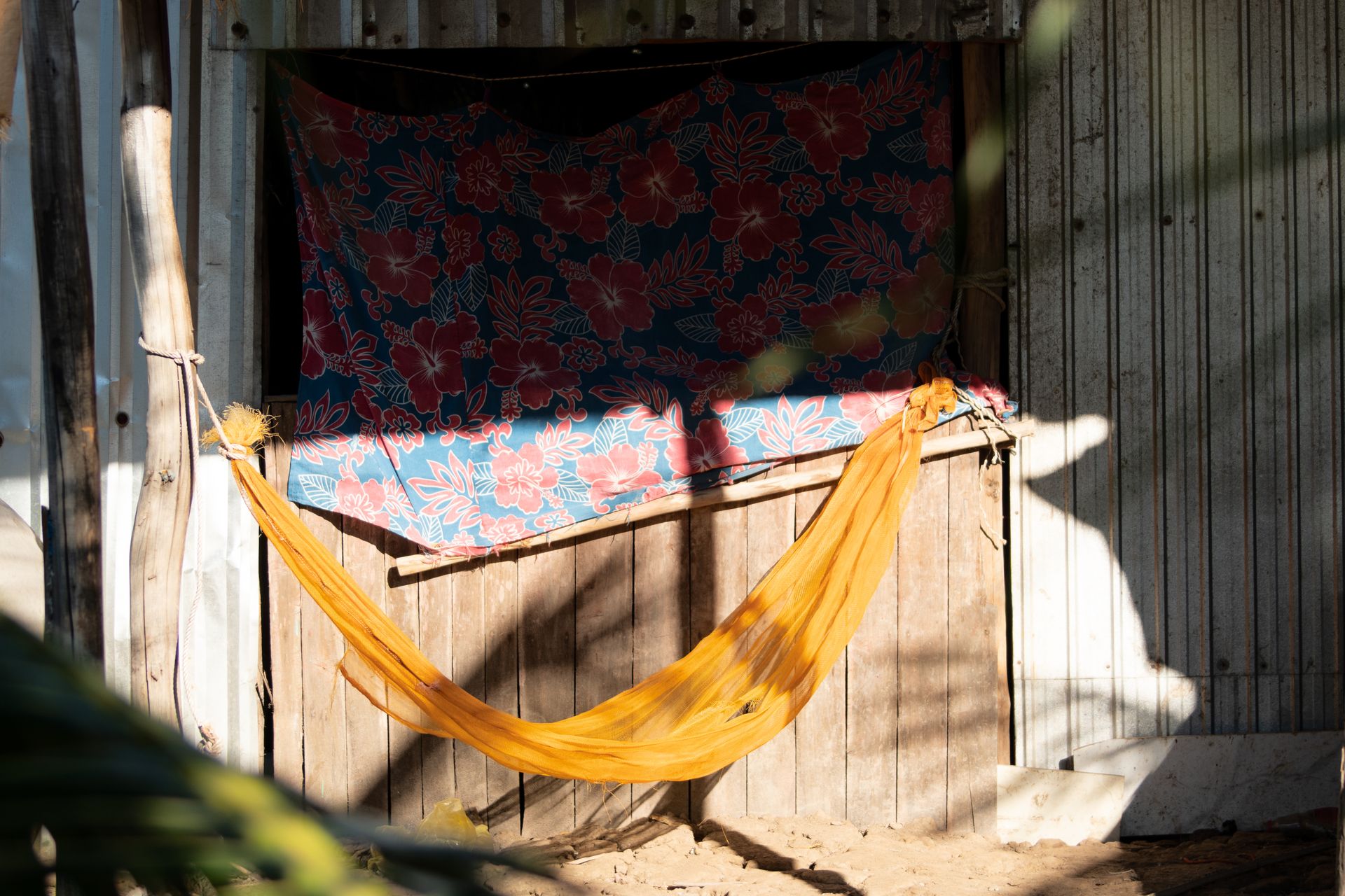 A vibrant yellow hammock in rural Vietnam casts shadows, evoking simple living and tropical relaxation.