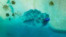 Stunning aerial shot of crystal-clear turquoise waters in Maldives with a floating structure.
