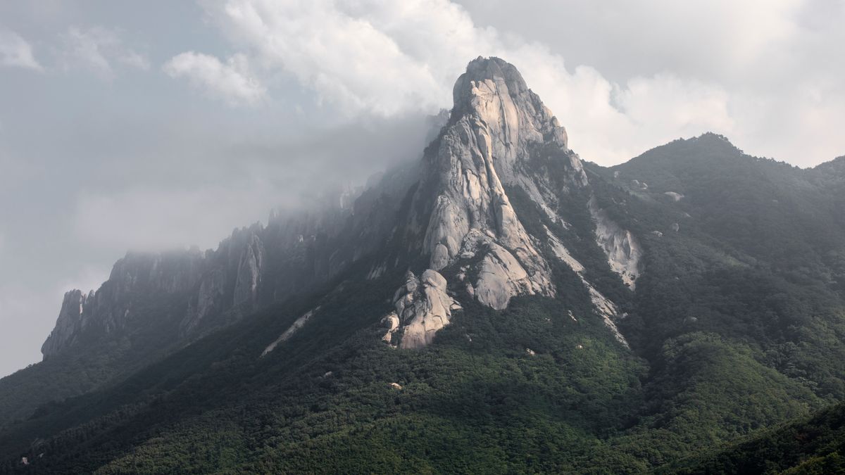 제주 동부 하루 — Stunning view of Seoraksan Mountain with rugged peaks and lush green foliage under cloudy skies.