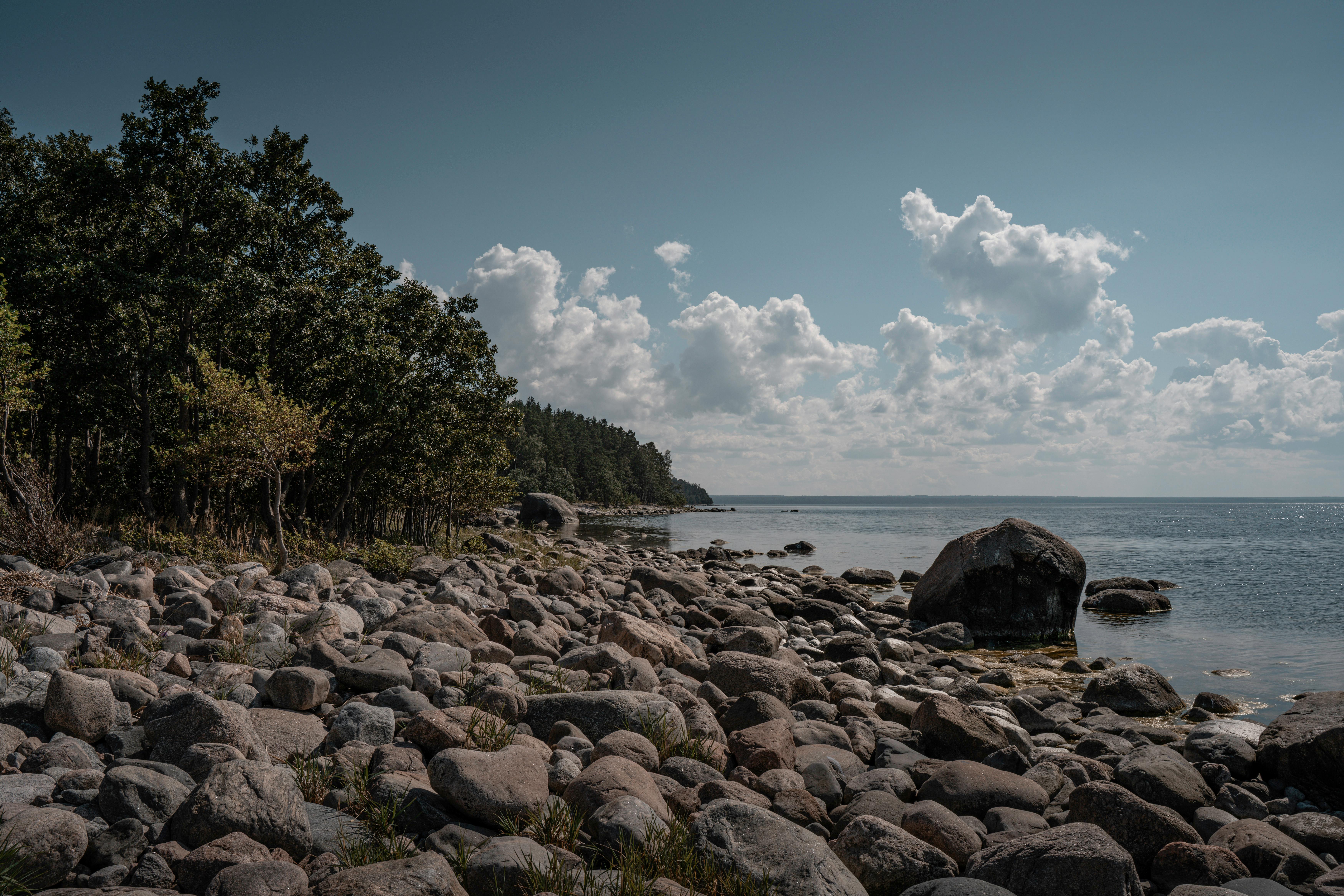 Scenic view of Käsmu's rocky shoreline and serene sea under a blue sky with clouds.