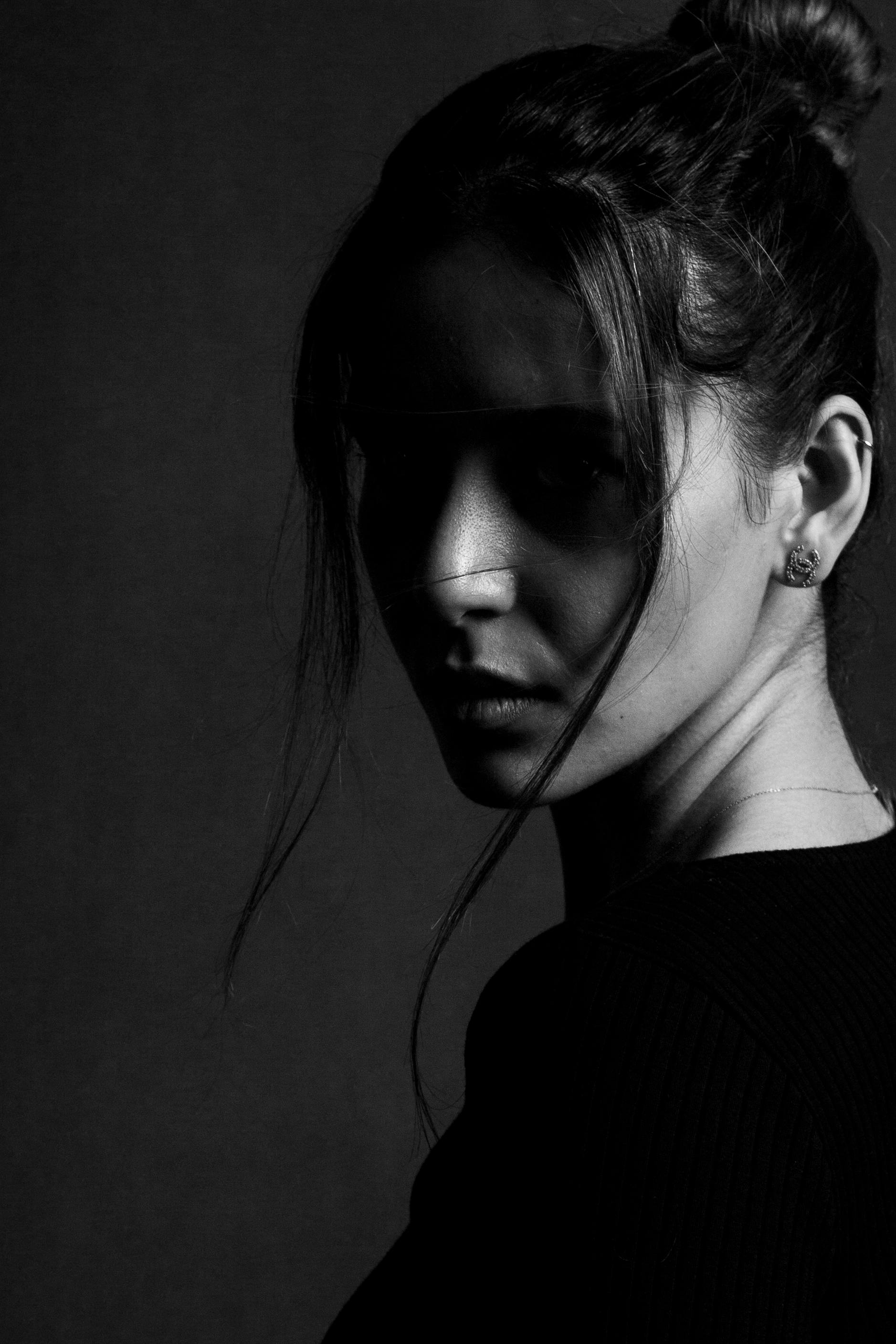 Moody black and white portrait of a woman casting shadow on her face.