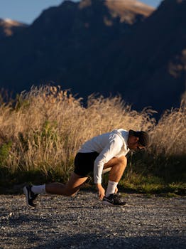 Athlete in sunset light, ready to sprint outdoors in stunning New Zealand landscape.