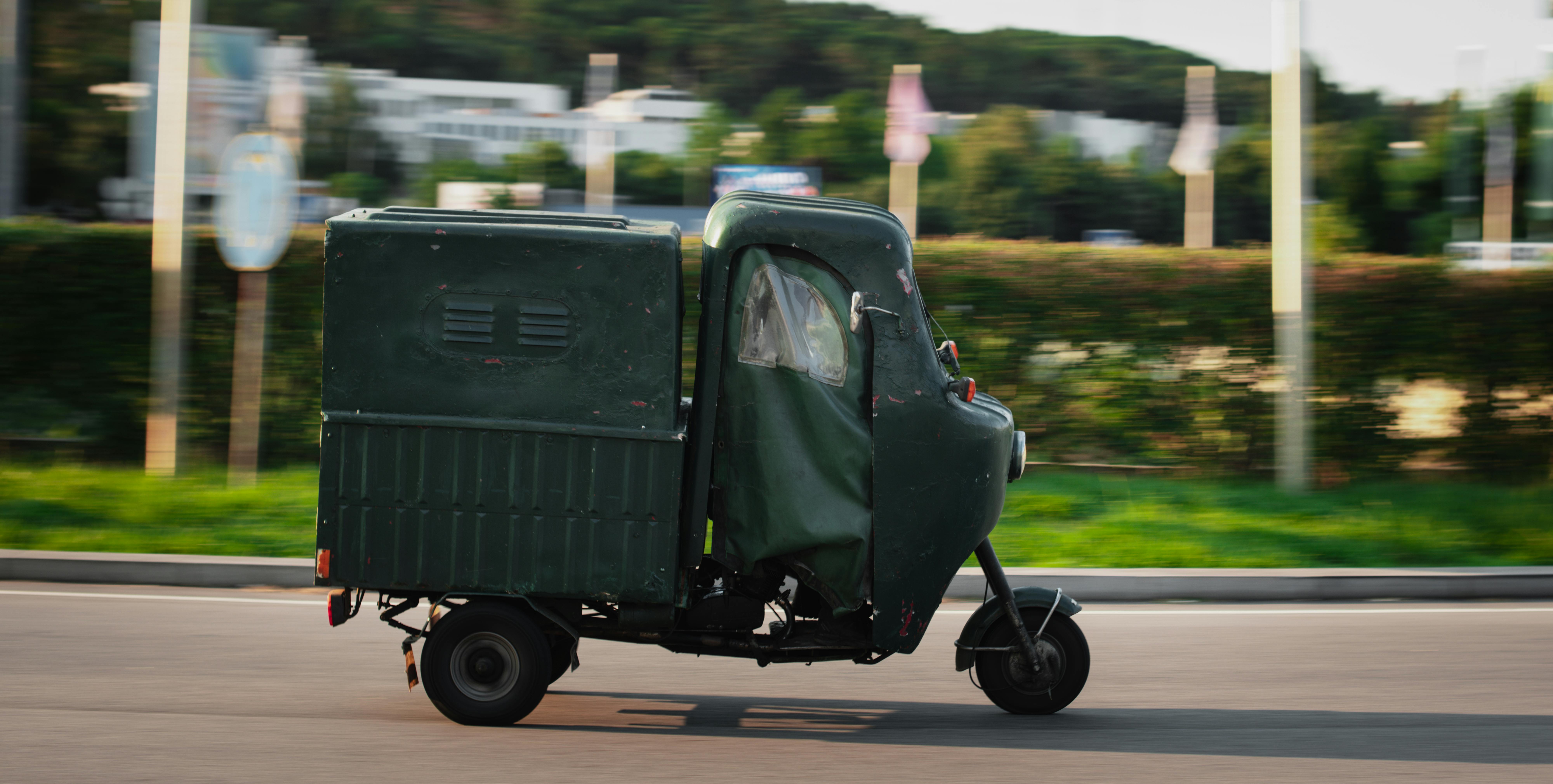 A classic three-wheeled vehicle driving on road in Braga, Portugal, showcasing vintage charm.