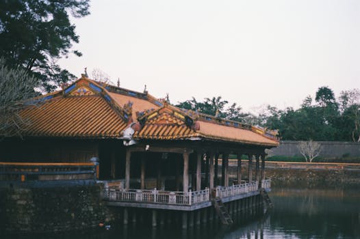 Serene view of a traditional Asian pavilion by a calm lake with lush greenery.
