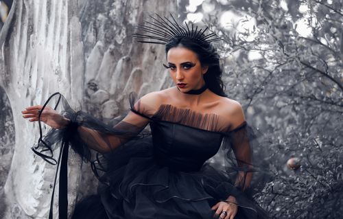 Free A bold and dramatic portrait of a woman wearing an elegant black dress in a moody outdoor setting. Stock Photo