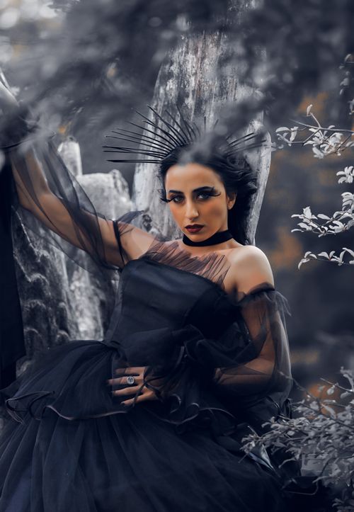 Free A dramatic gothic portrait of a woman in elegant black attire amidst a natural setting, evoking a moody aesthetic. Stock Photo