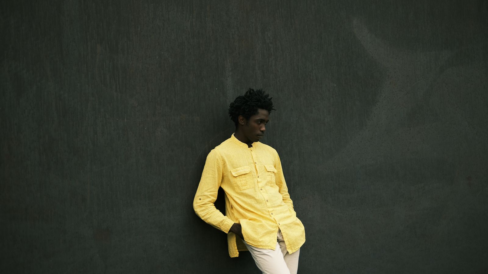Young man in yellow shirt against dark backdrop, Benin