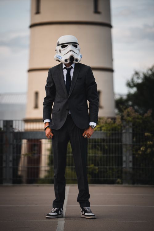 Free A person in a suit and stormtrooper helmet poses outdoors near a tower in Gütersloh, Germany. Stock Photo