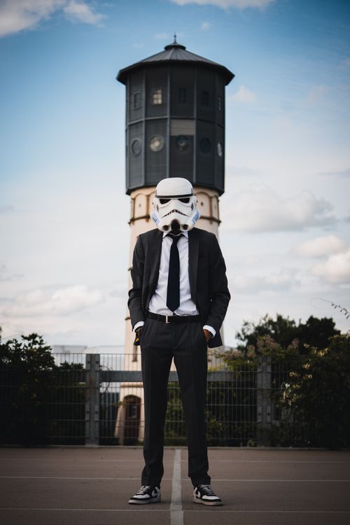 Free Person in a Stormtrooper helmet suit posing in front of a clock tower in Gütersloh. Stock Photo