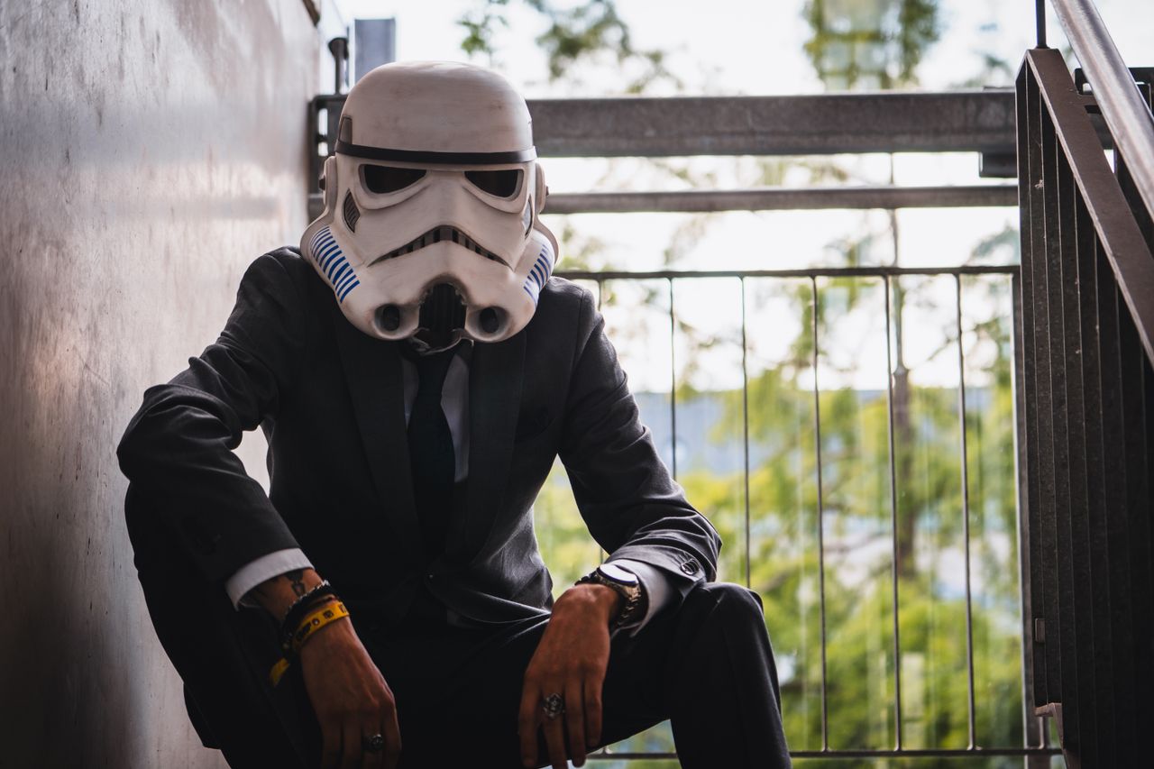 a person wearing a stormtrooper helmet and suit poses casually outdoor