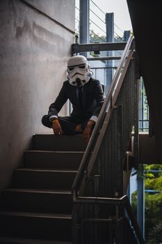 A man wearing a stormtrooper helmet poses in a suit on a stairway.