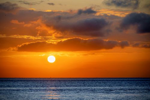 Free Serene sunset over the ocean with vivid orange and blue hues, capturing the tranquility of nature. Stock Photo