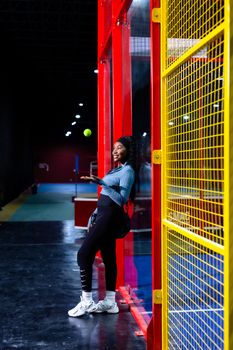 A woman practicing padel on an indoor court with vibrant colors.