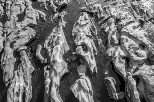Free Eroded rock formations with water in black and white, captured from above, showcasing unique geological patterns. Stock Photo