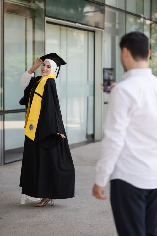 Free Young graduate posing in cap and gown, joyfully celebrating achievement. Stock Photo