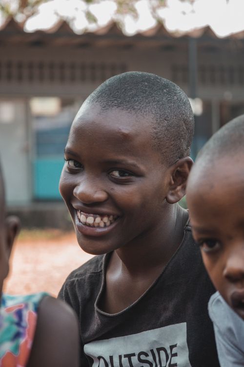 Free Group of African children smiling happily outside a building, capturing pure joy and friendship. Stock Photo