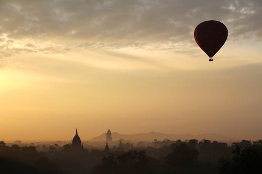 Hot air balloon gracefully glides over Bagan temples at sunrise, capturing serene adventure.