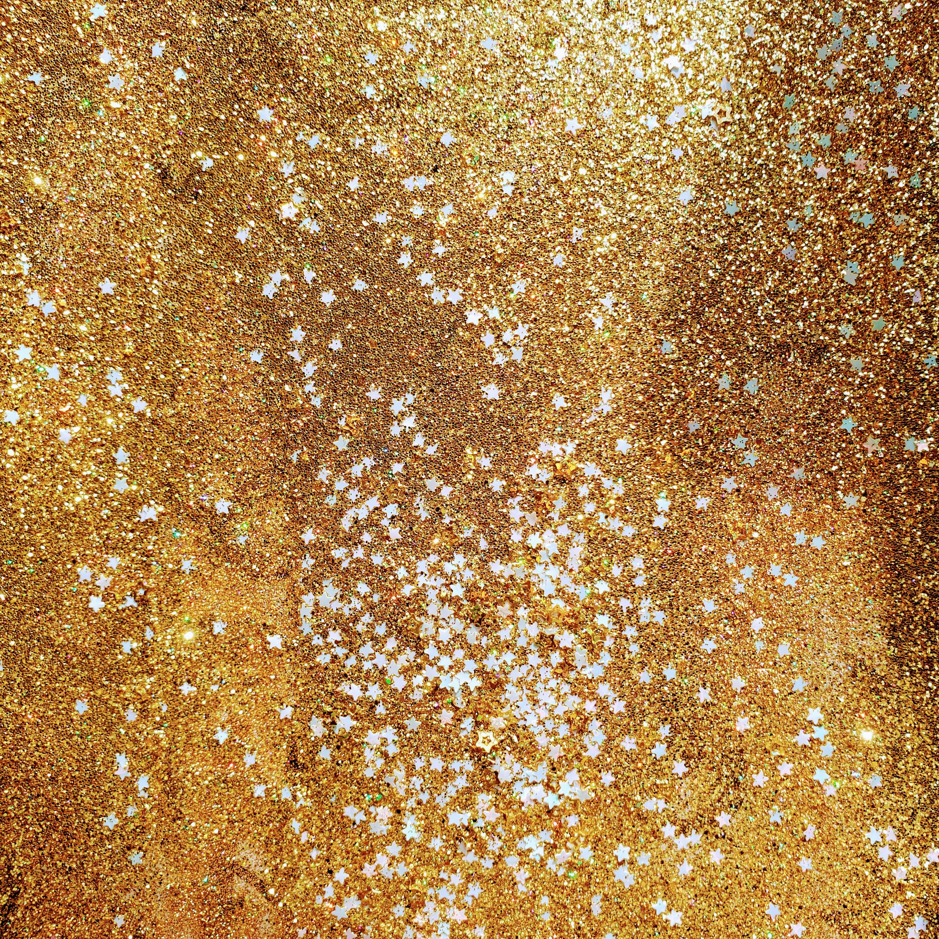 A vibrant display of golden glitter with white star shapes, perfect for festive occasions.