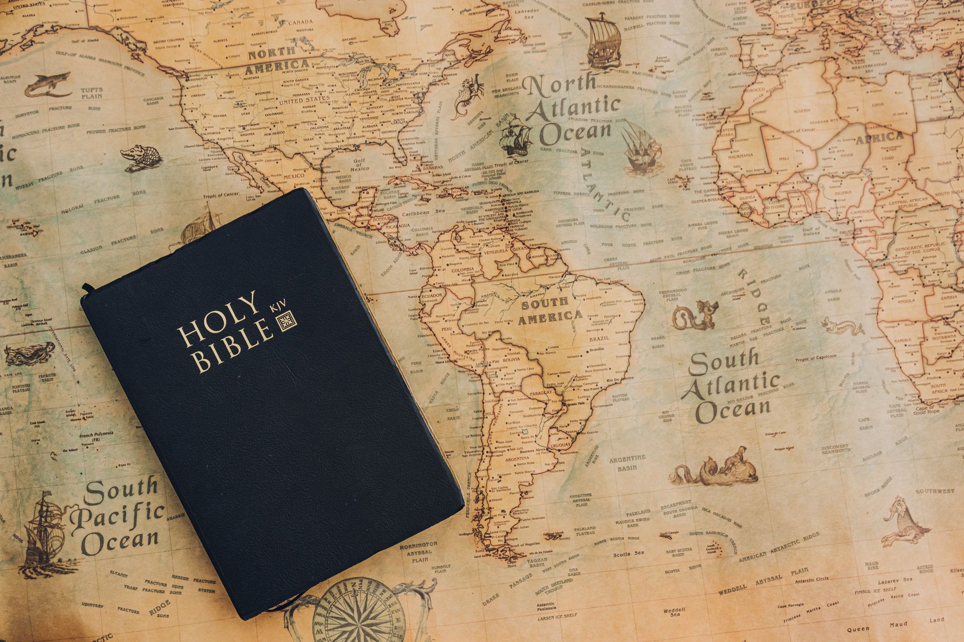 A classic King James Bible placed on a vintage world map highlighting continents.