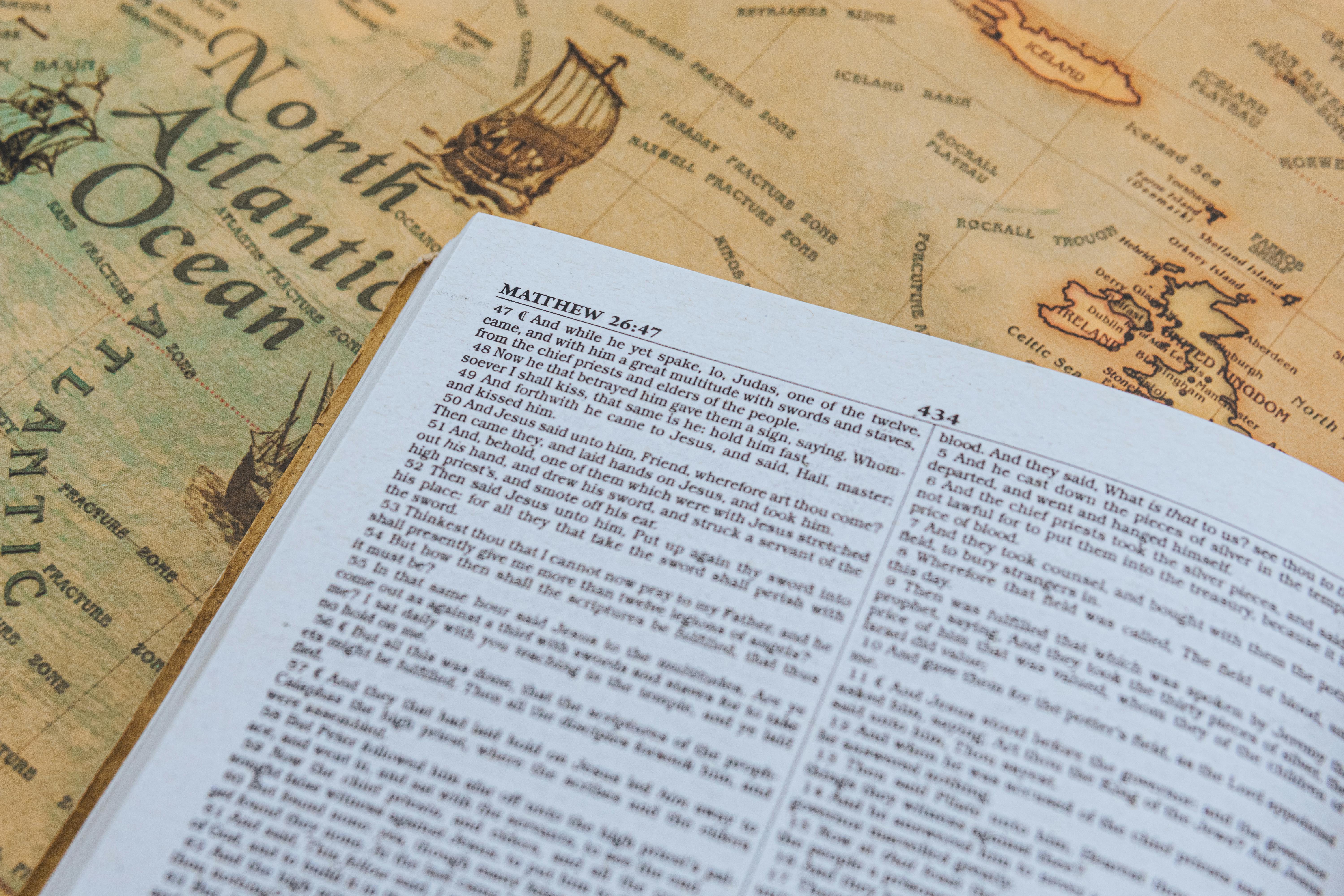 Open Bible with text from Matthew 26:47 on vintage map of North Atlantic Ocean.