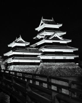 Black and white night photo showcasing a traditional Japanese castle's intricate architecture.