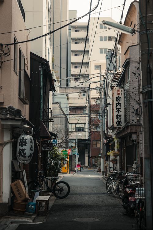 Free A narrow alleyway in Tokyo featuring bicycles, signs, and urban architecture. Stock Photo