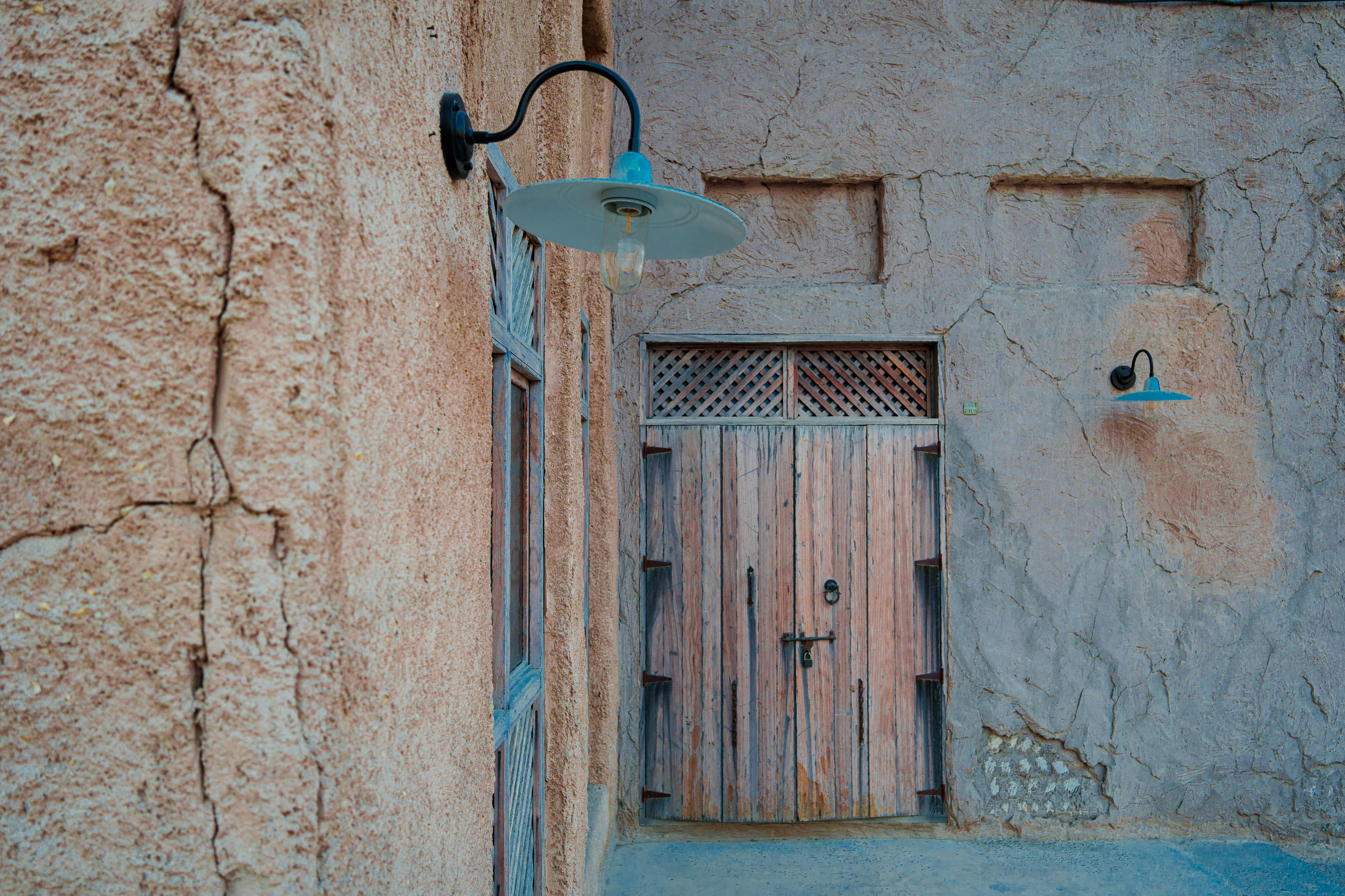 Rustic wooden door in old Dubai with vintage lamps on a textured wall.