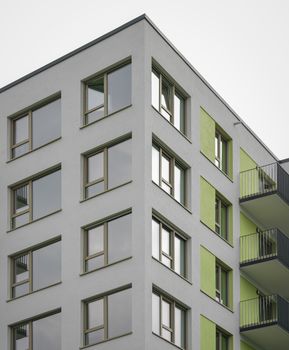 Close-up of a contemporary apartment building with unique green accents and balconies.