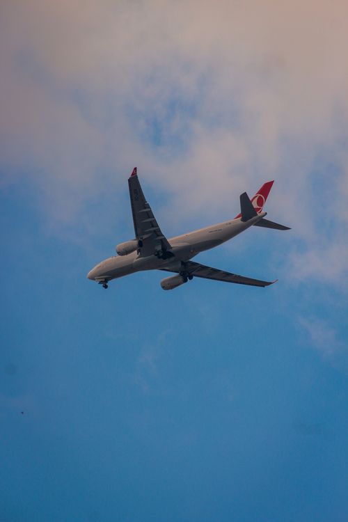 Free A commercial airplane in mid-flight against a backdrop of blue sky and soft clouds. Stock Photo