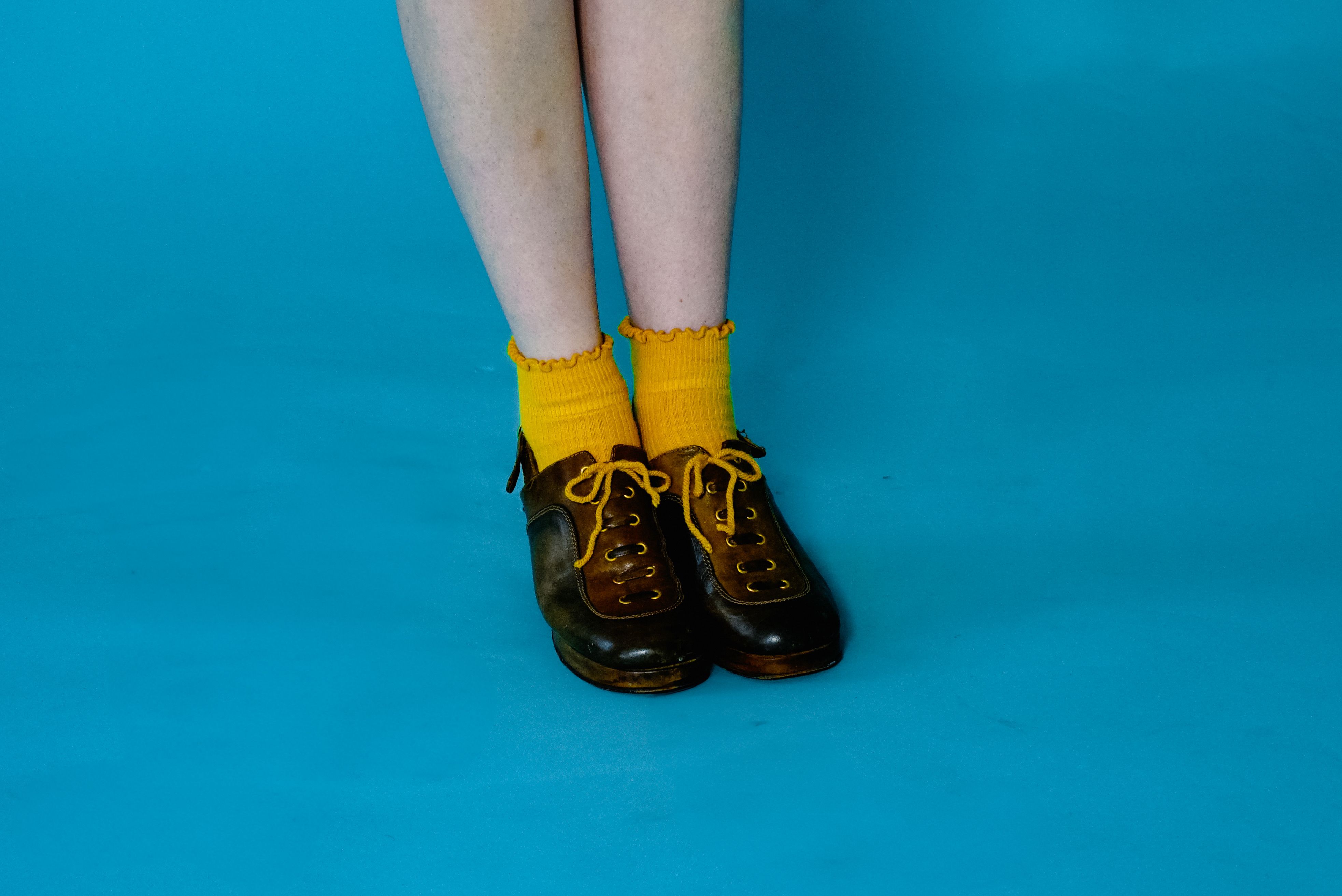 Bright yellow socks and vintage shoes on a bold blue floor create a colorful contrast.