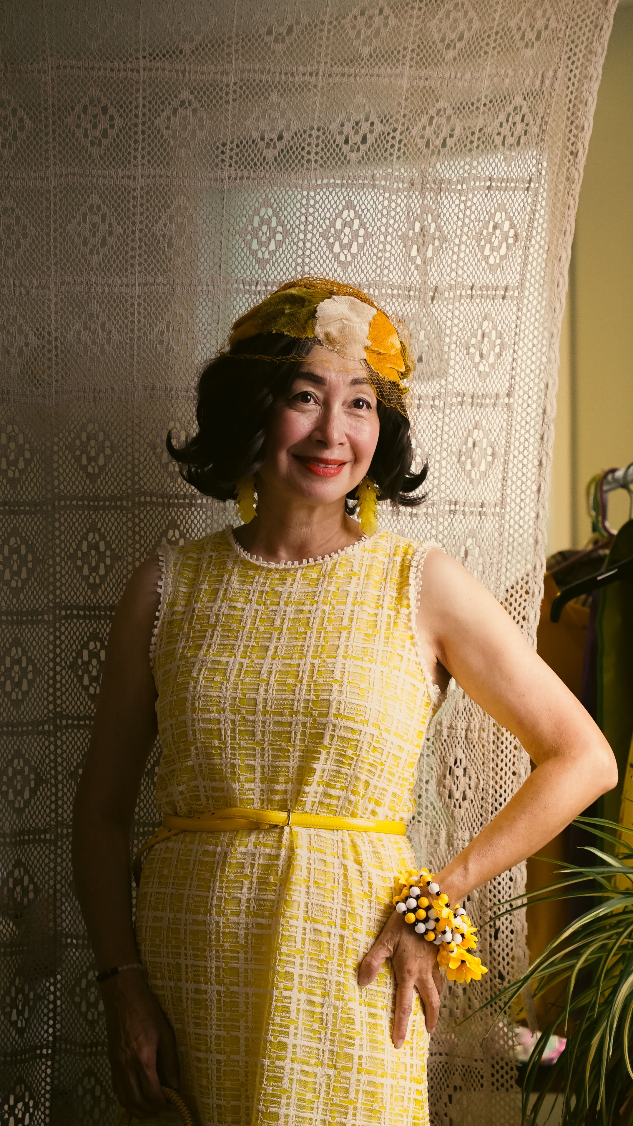 Charming woman in a vintage yellow dress with floral accessories, smiling indoors.