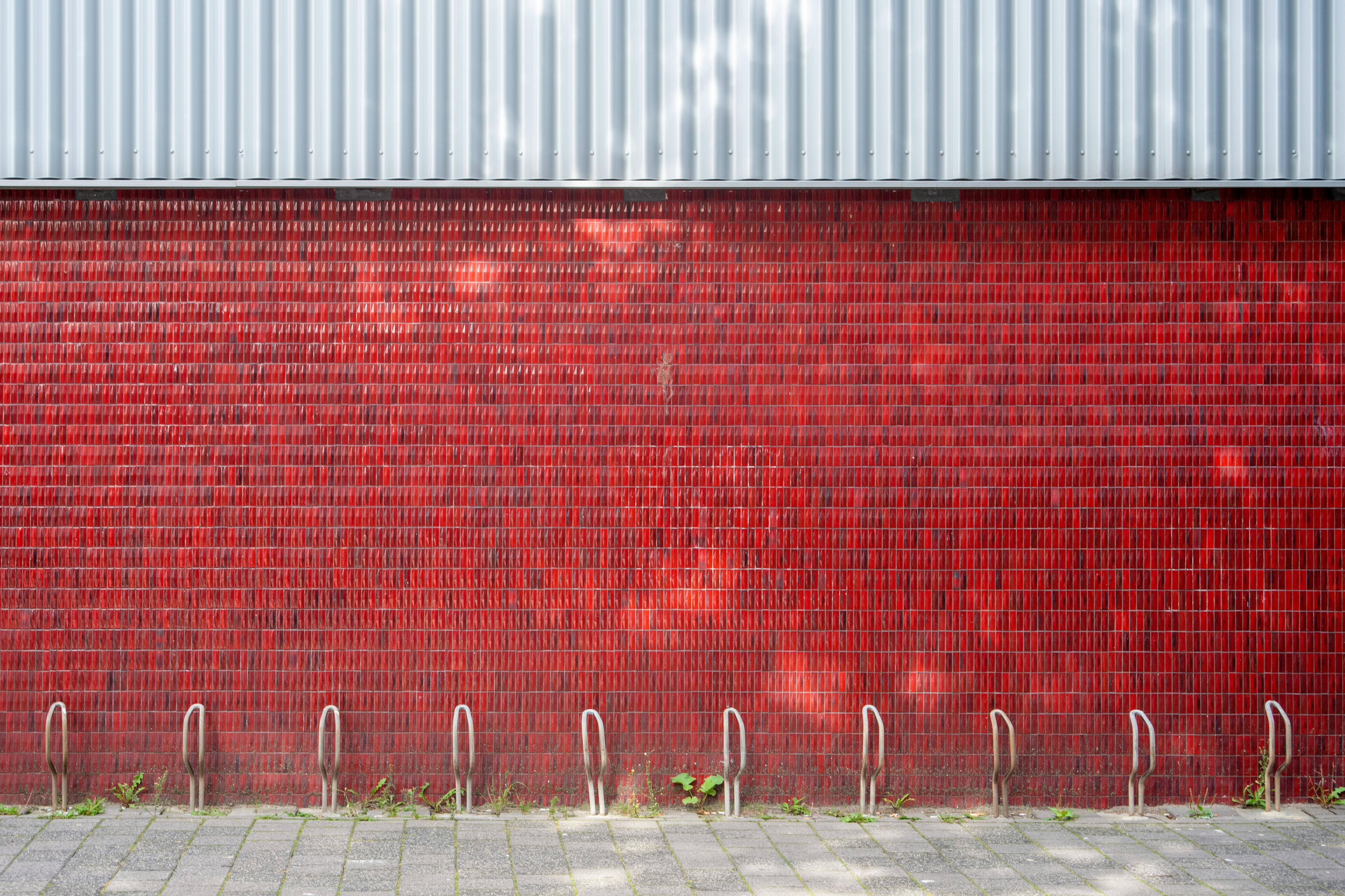 Un mur de briques rouges extérieur avec des supports à vélos en métal vides sous la lumière naturelle du jour. - illustration