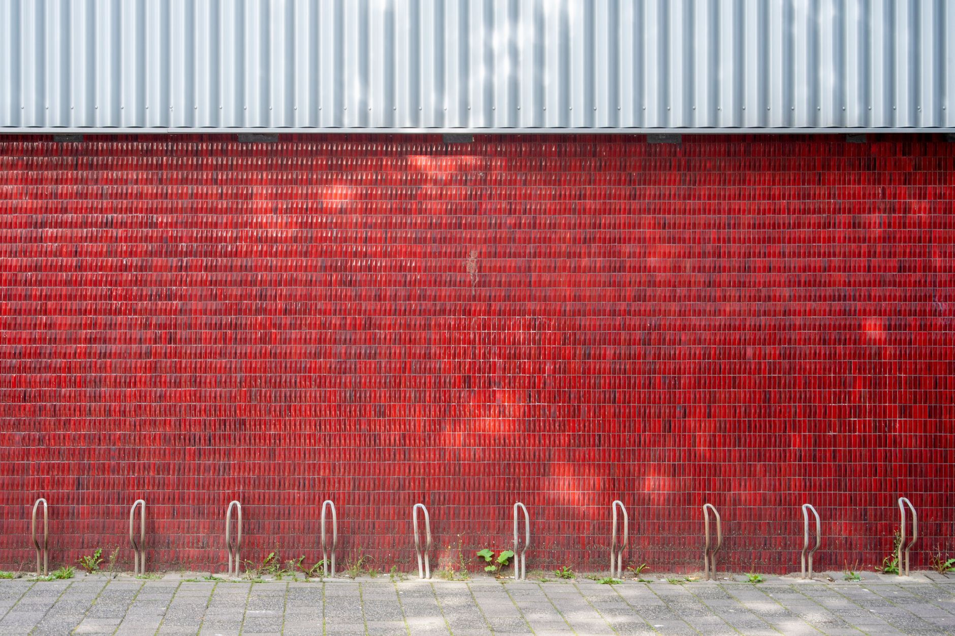 Un mur de briques rouges extérieur avec des supports à vélos en métal vides sous la lumière naturelle du jour. - illustration