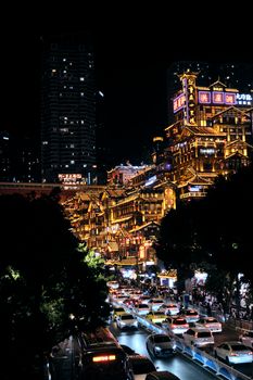 Dynamic view of Chongqing's illuminated buildings and bustling street at night.