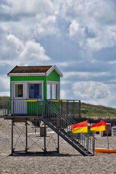 Vibrant lifeguard station with red and yellow flags on a sunny beach day.