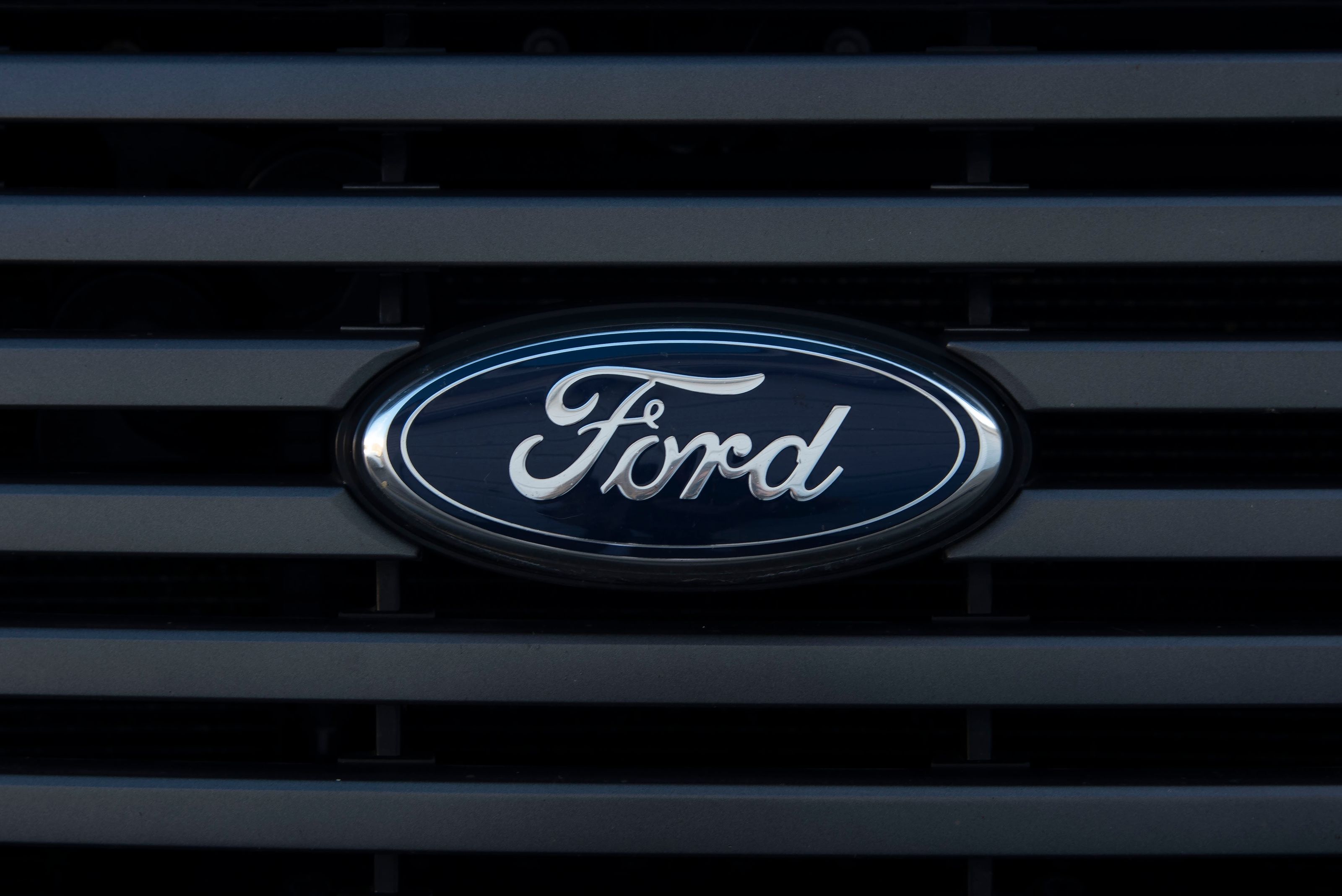 Detailed view of a Ford emblem mounted on a vehicle grille, showcasing modern design.