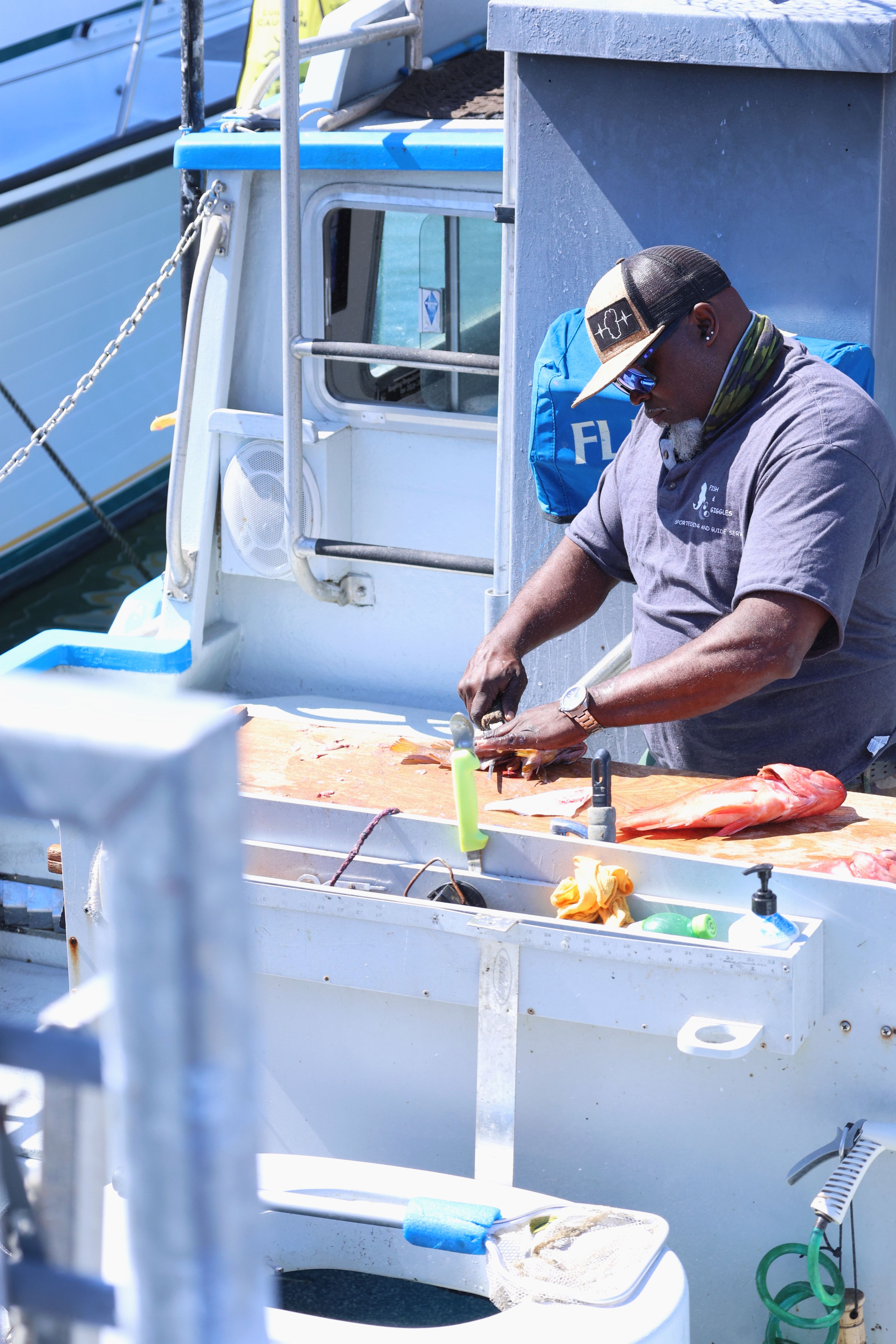A fisherman fillets fresh seafood on a boat in San Francisco, California. Bright day at the dock.