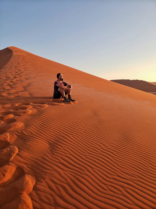 Free Man Sitting on Desert Stock Photo