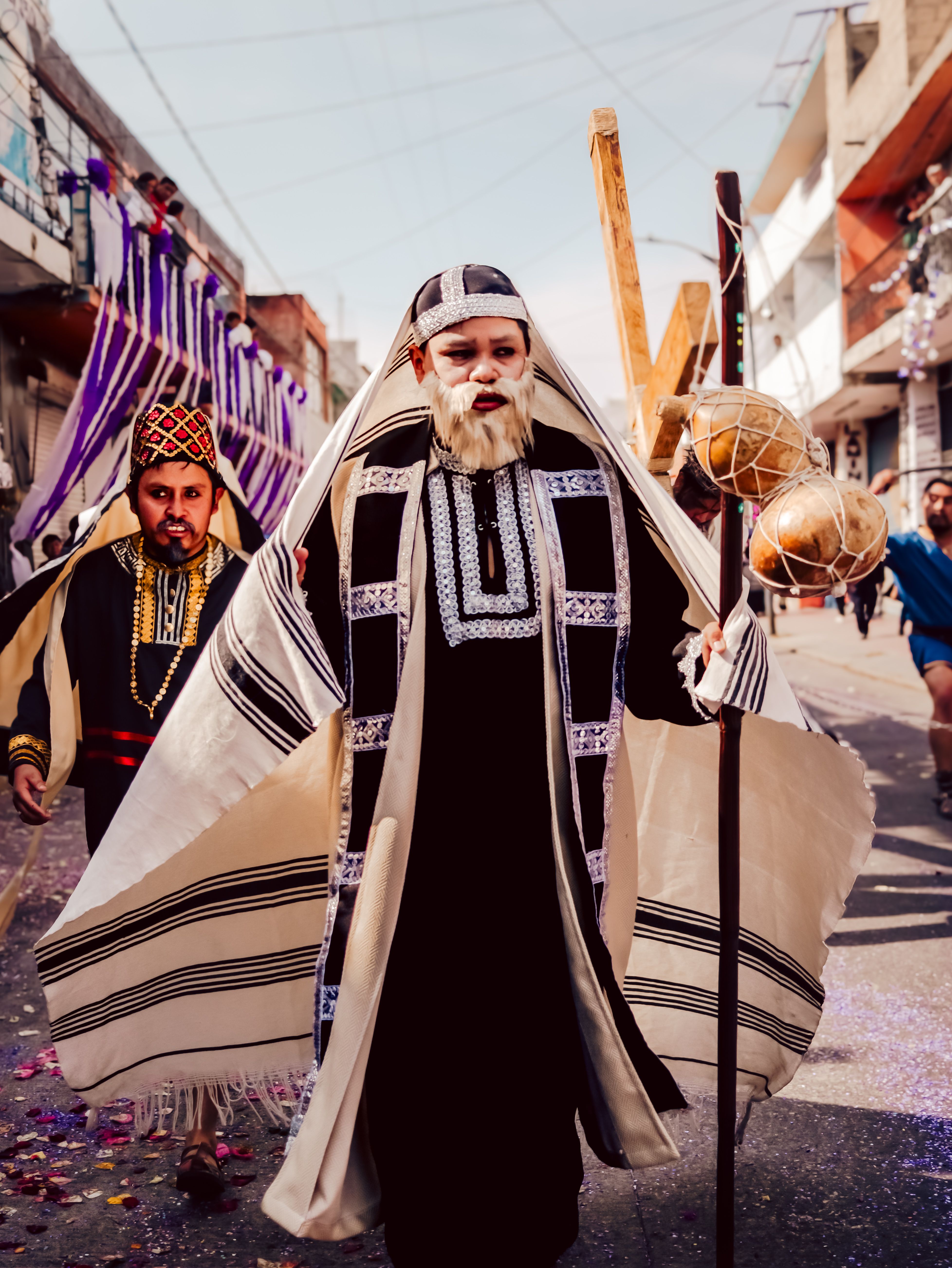 Colorful religious procession with people in traditional costumes in a vibrant street setting.