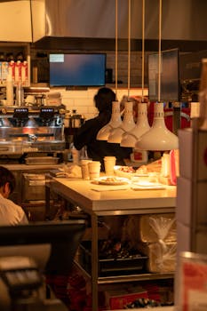 Warm lighting in a busy cafe kitchen with chefs at work, Illinois, USA.