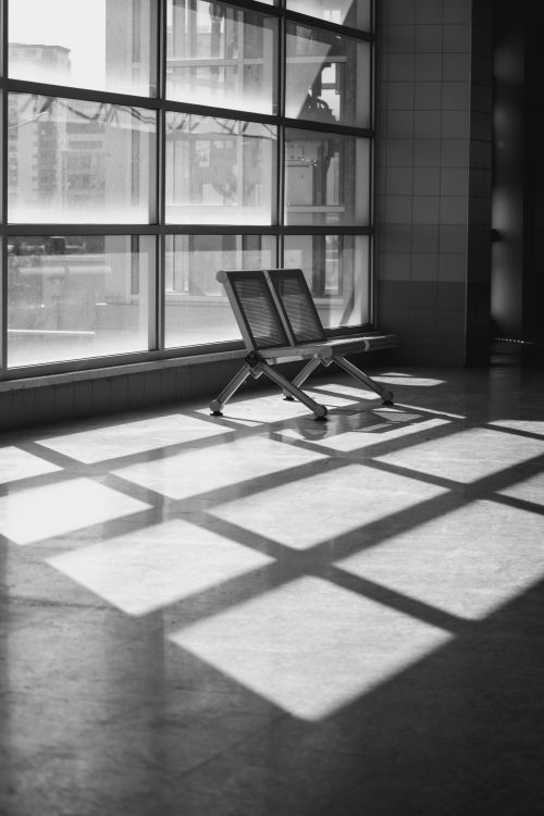 Free Lonely metal bench in a sunlit room casting geometric shadows on the floor. Stock Photo