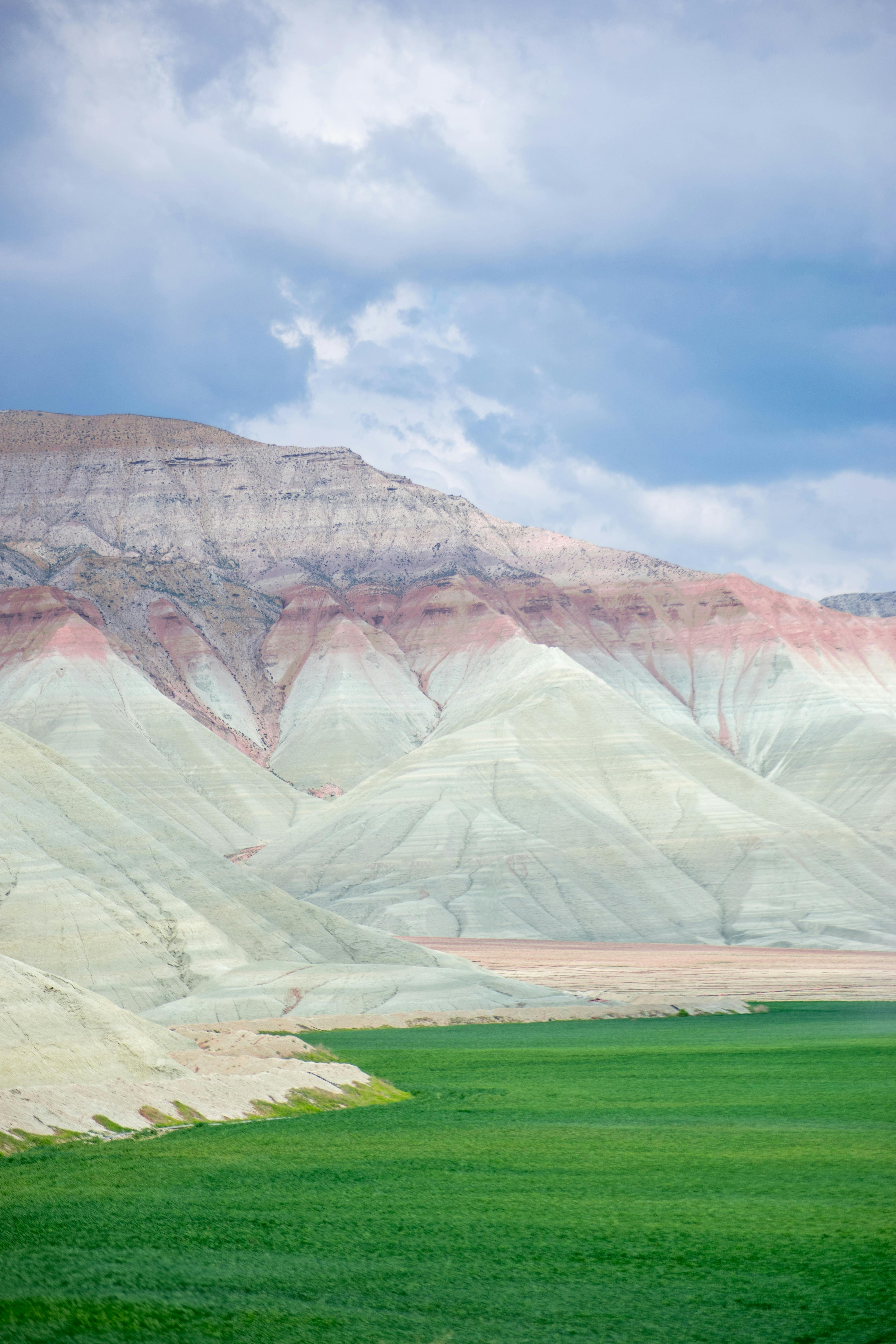 A breathtaking view of a unique striped mountain range against a cloudy sky, vibrant and serene.