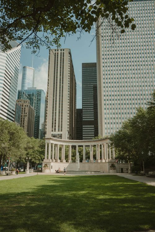 Free View of Wrigley Square in Millennium Park, Chicago, with lush greenery and towering skyscrapers. Stock Photo