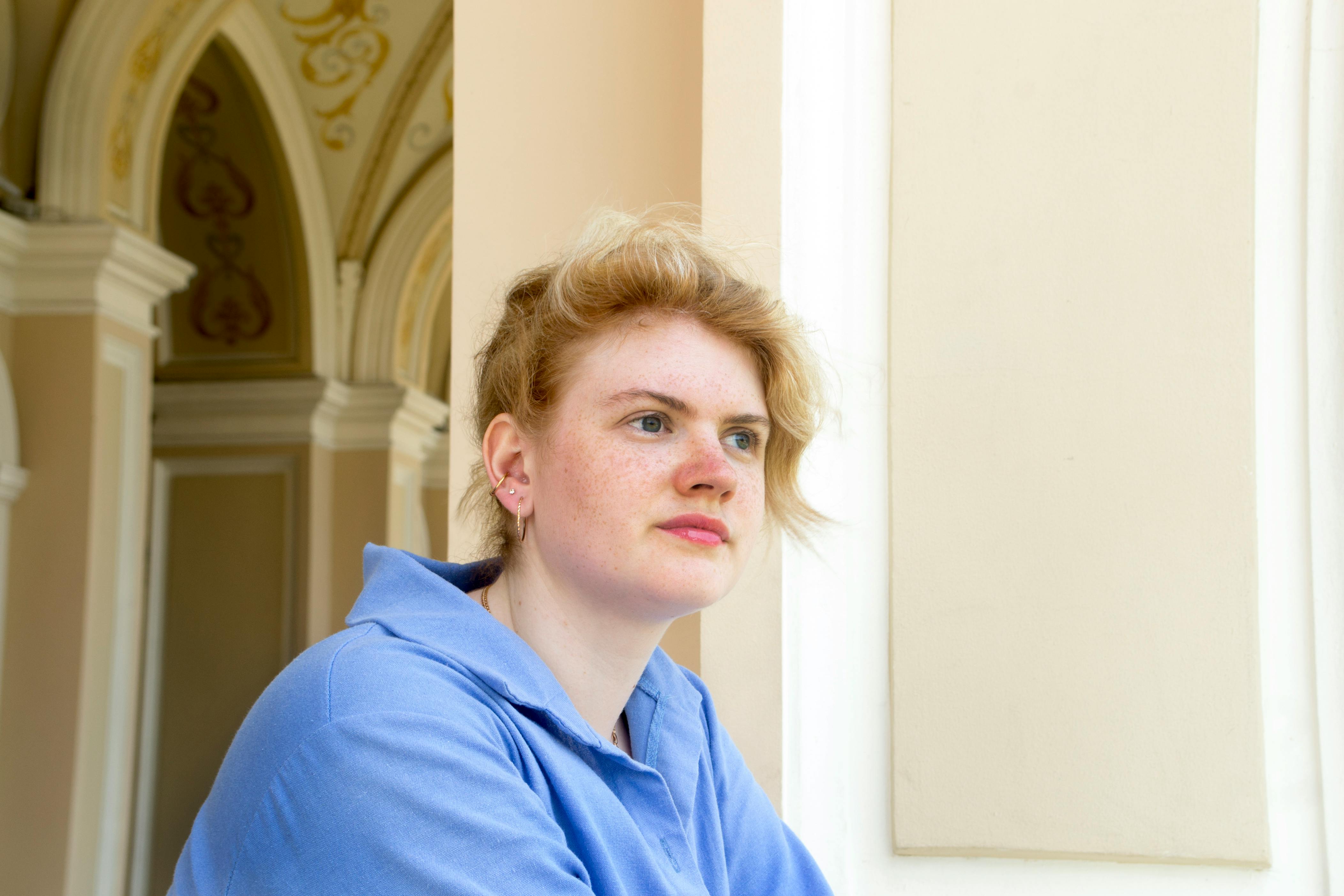 Kostenlos Junge Frau im blauen Hemd grübelt in einem reich verzierten Flur in Odessa, Ukraine. Stock-Foto